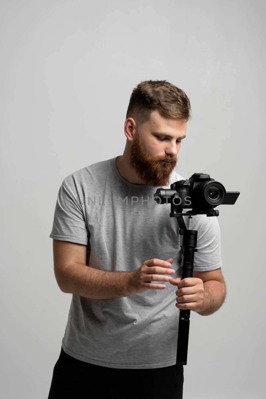 Professional bearded videographer filmmaker cinematographer dop holding camera which set on 3-axis gimbal. Pro equipment helps to make high quality video without shaking. by vovsht