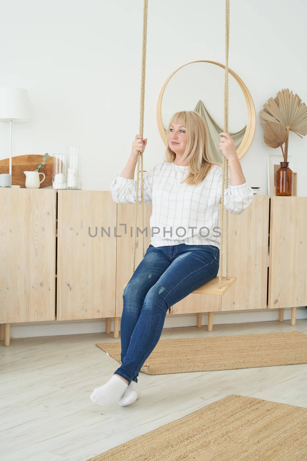 Beautiful mature woman swinging on swing. Middle-aged blonde happy female by NataBene