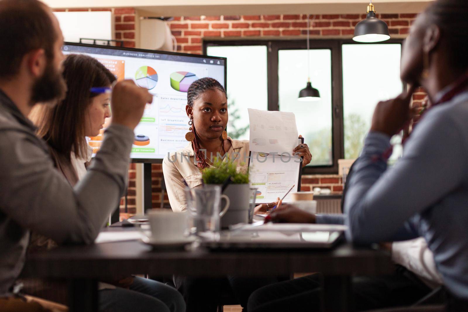 Businesspeople sitting at meeting table discussing management strategy working at company presentation in startup office. Diverse entrepreneurs brainstorming ideas for marketing project