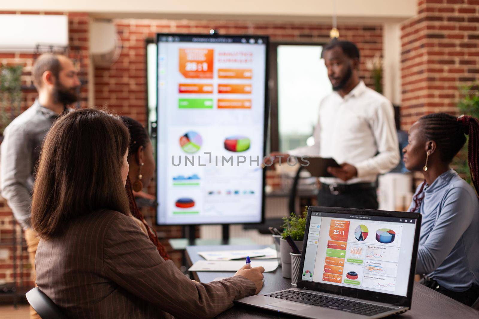 Businesspeople sitting at meeting table in startup company office brainstorming project ideas working at management presentation. Entrepreneurs discussing business strategy at workplace