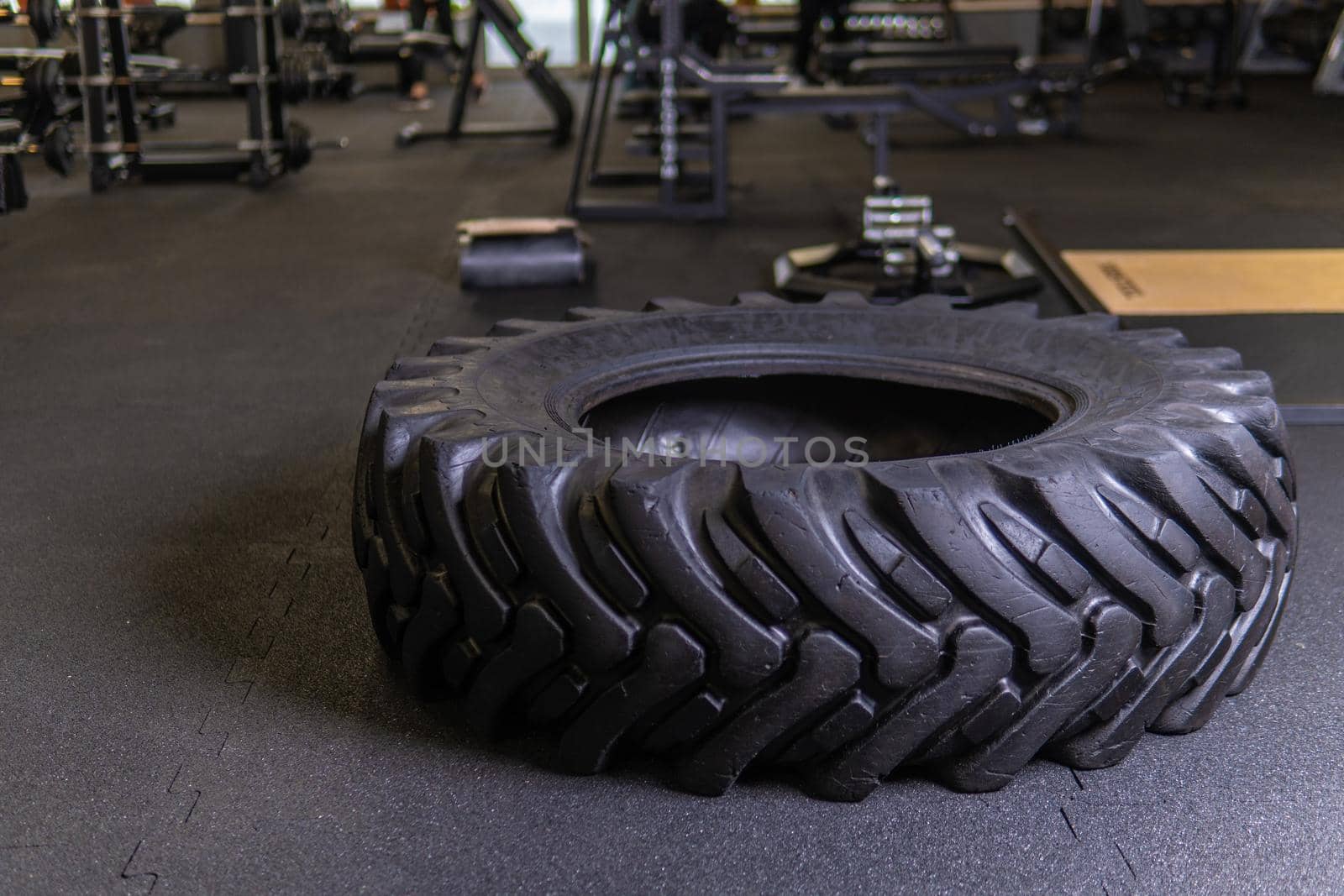 A tire on a black background with a sledgehammer lies for crosfit fitness wheel sledgehammer workout black tire, from fit exercise in adult concentration push, big activity. Sweat dedication up,