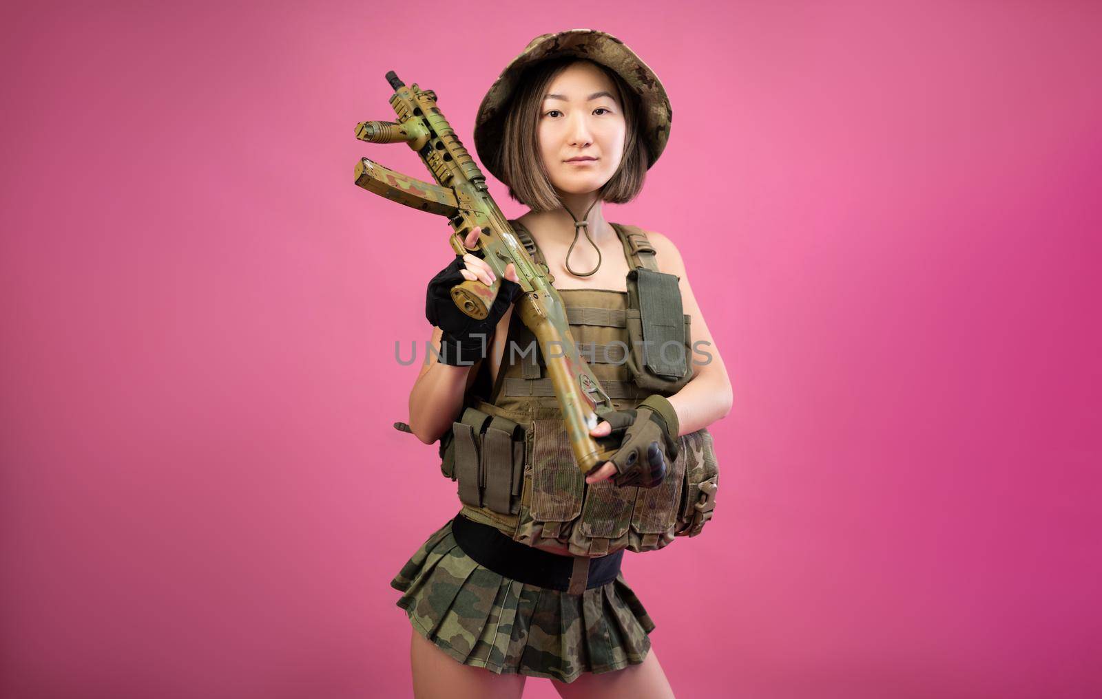 sexy Asian woman in military clothes with an automatic rifle in her hands while serving in the army by Rotozey