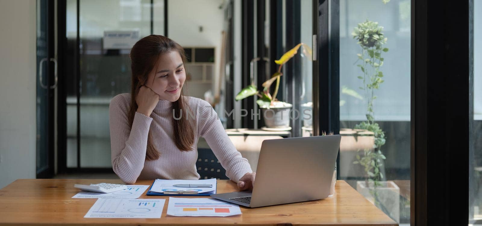 Smiling young asian businesswoman using computer at home office workplace, happy korean employee working on laptop, attractive woman student studying communicating online with laptop computer