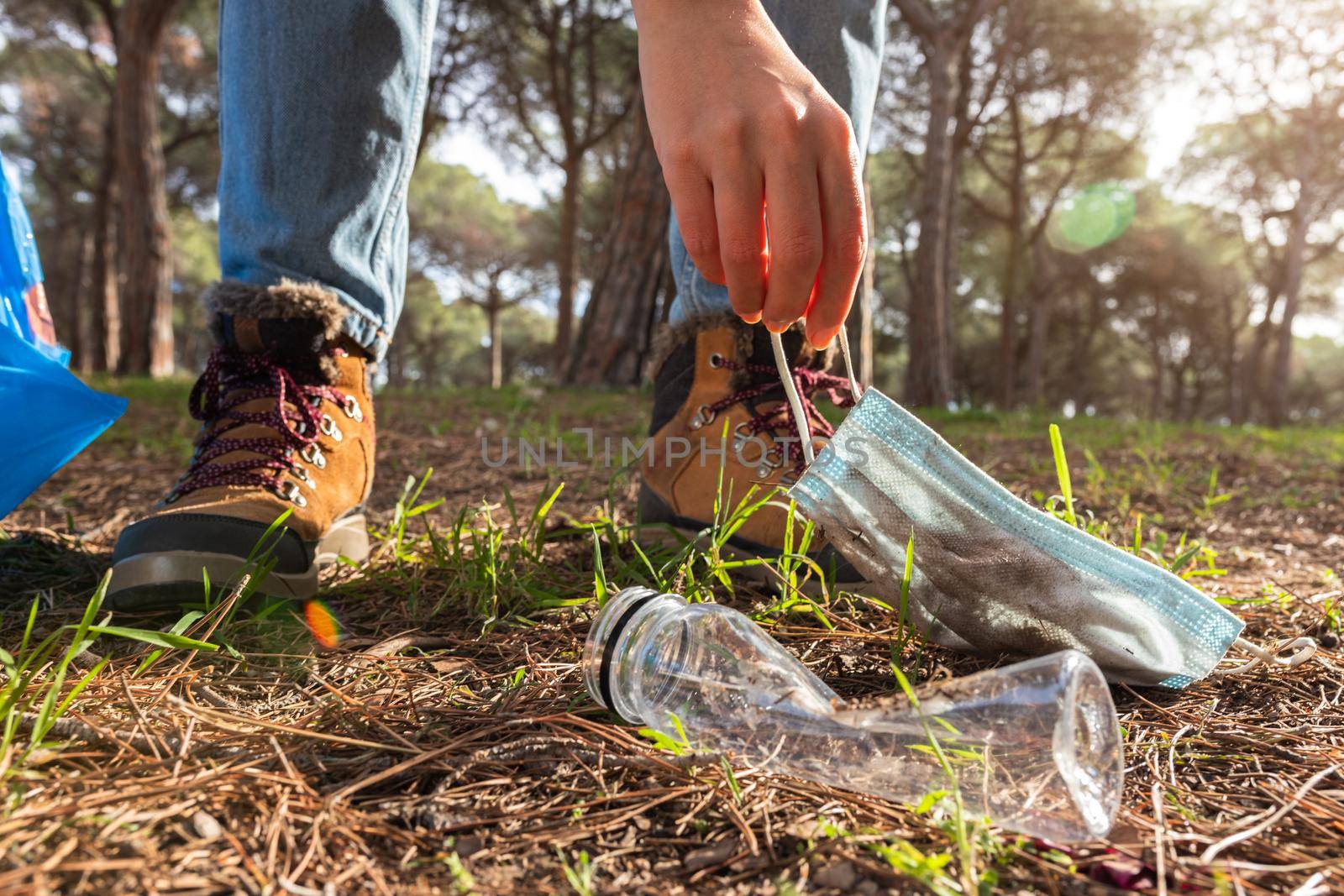 Close up of unrecognisable woman picking up trash to clean the forest. Environmental activist and ecology concept.