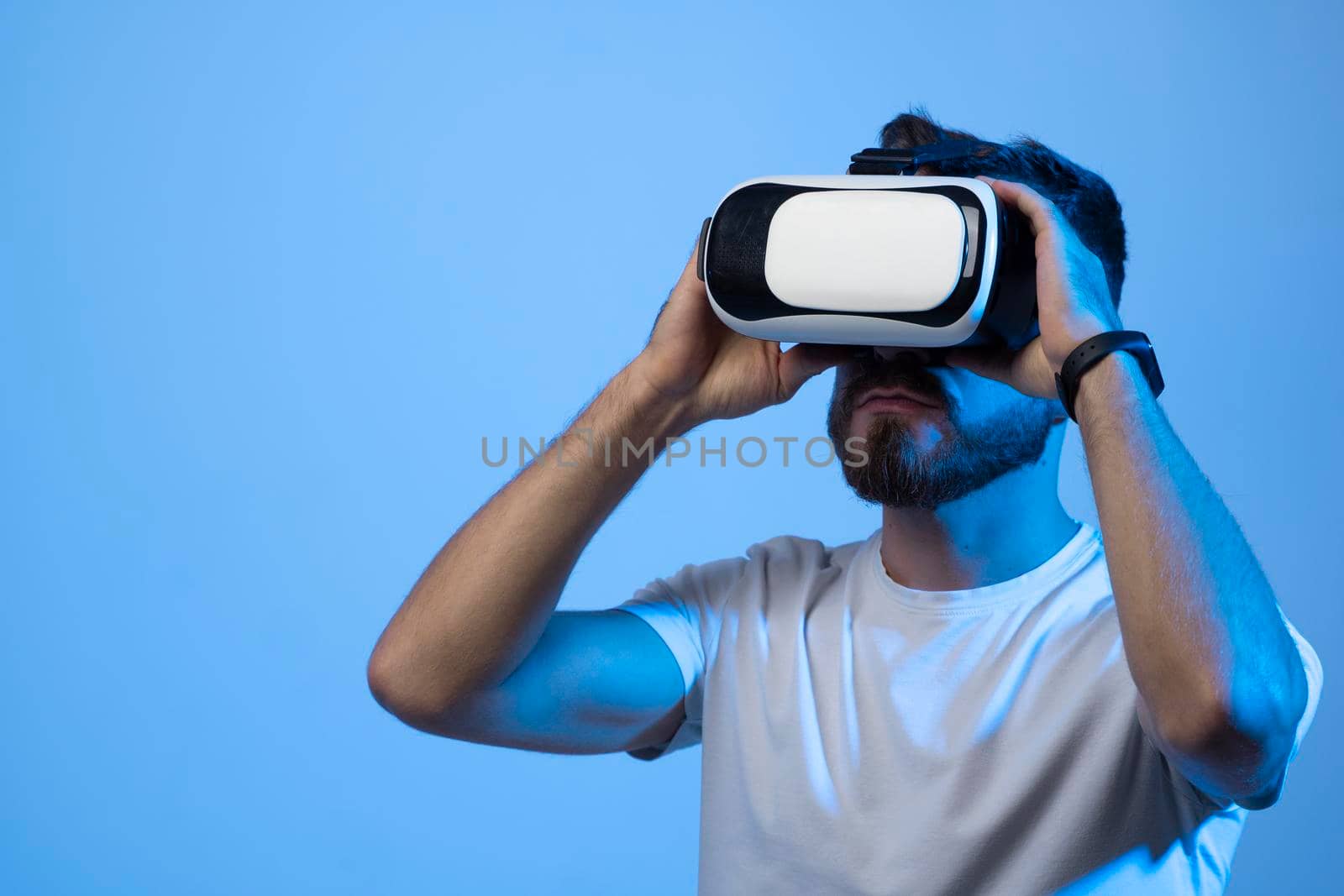 Close up portrait of young handsome attractive bearded man in vr glasses playing video games with virtual reality headset in a metaverse. by vovsht