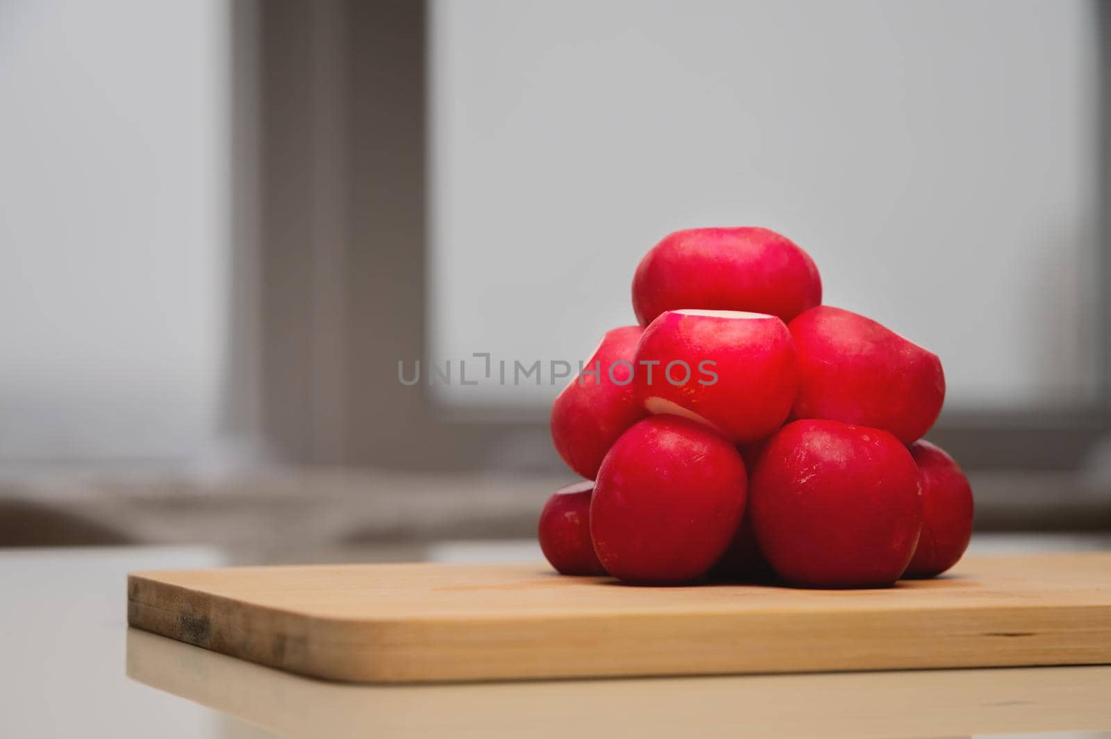 bright fresh bunch of radishes lies on a wooden board on the table by yanik88
