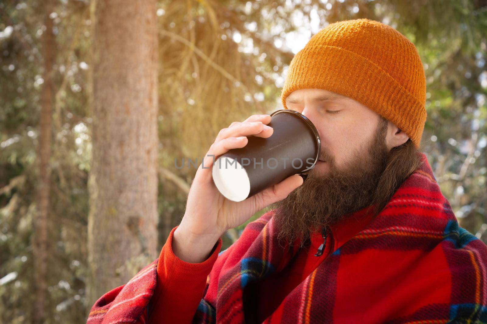 bearded men in a hat and plaid drinking a drink on the background of the forest by yanik88