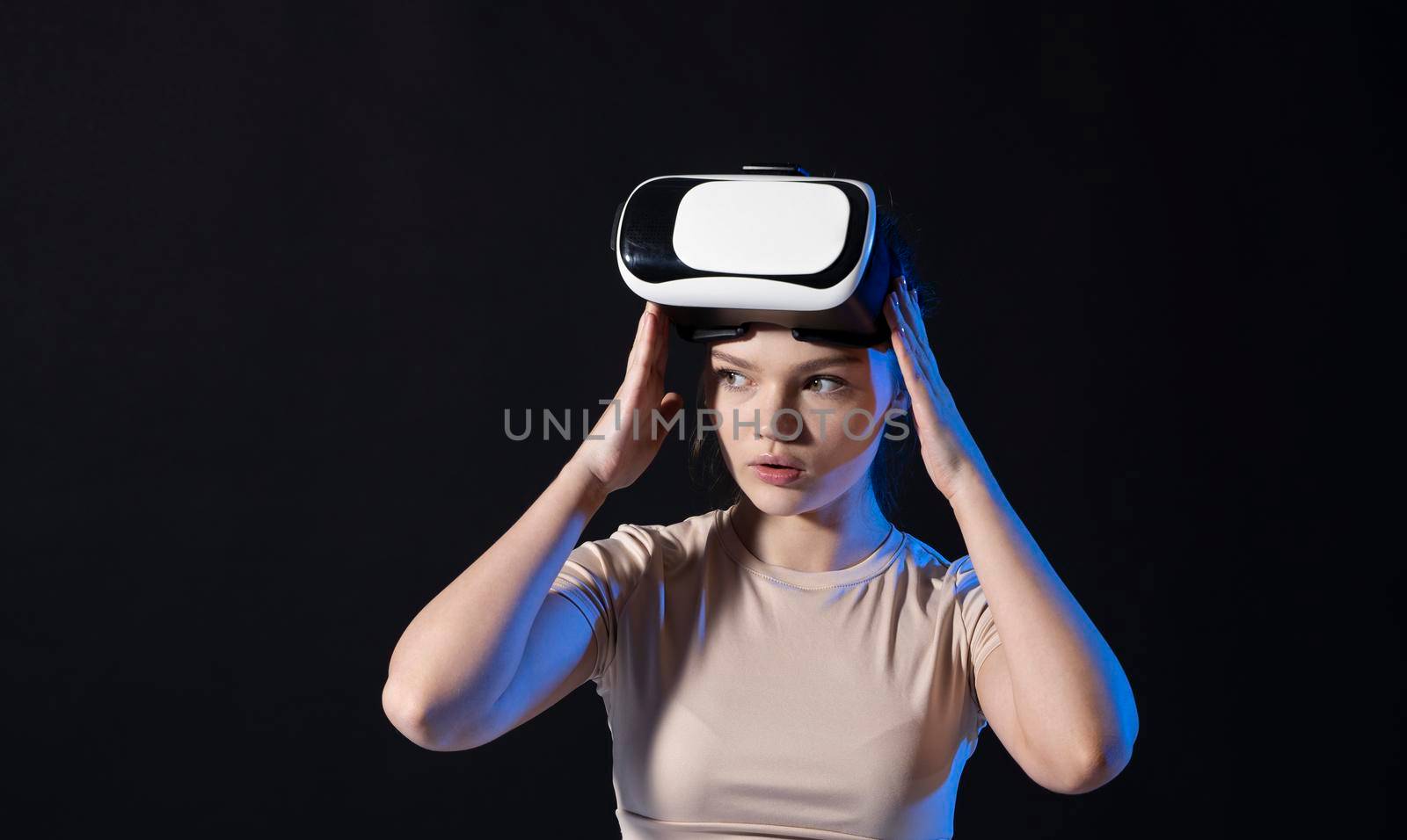 Brunette woman gamer with a virtual reality glasses ready to play a game or explore the environment in a metaverse world. Modern technologies