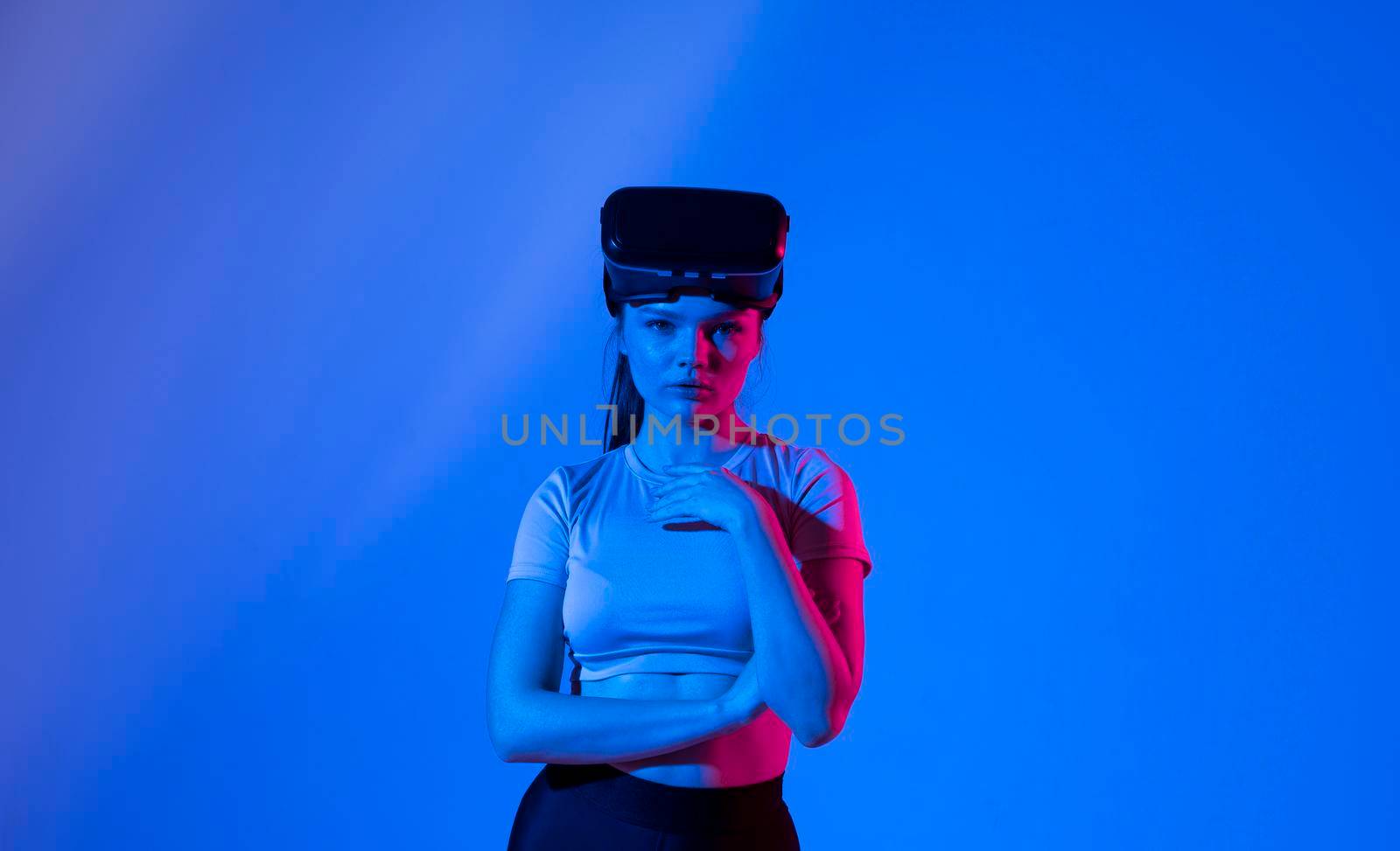 Beautiful brunette woman gamer with a virtual reality glasses ready to play a game in neon light. Modern technologies