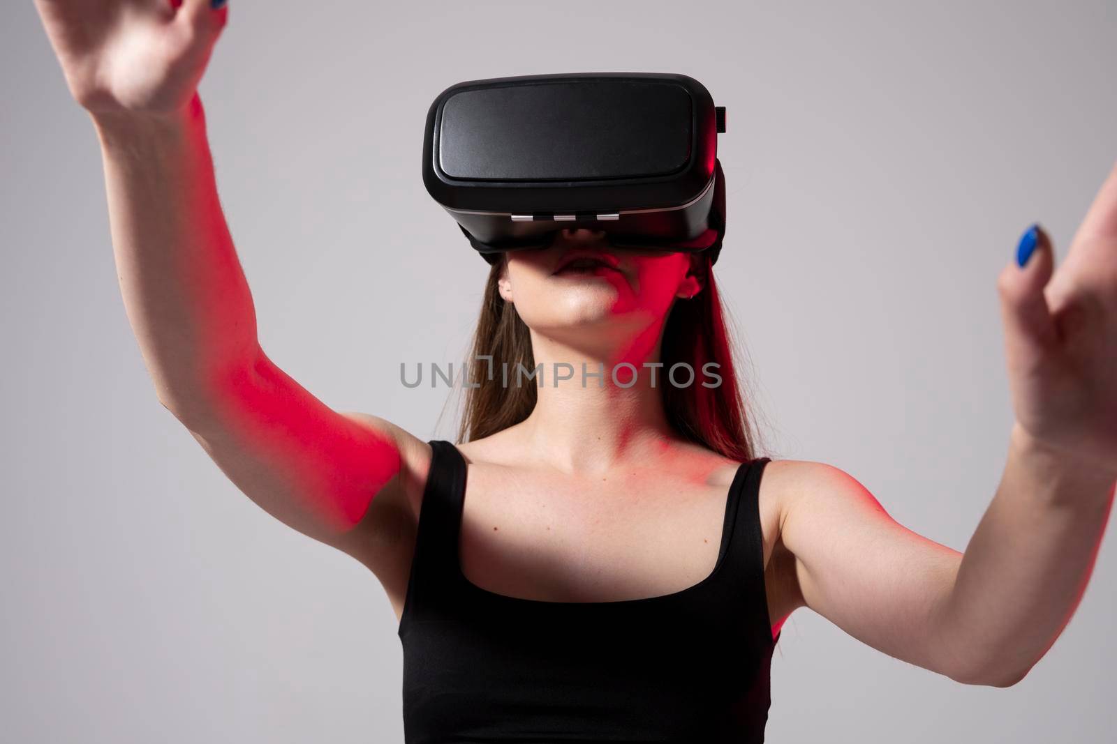 Beautiful attractive happy brunette woman in black t-shirt enjoying VR experience. Woman with VR headset touching invisible screen. Future technology concept