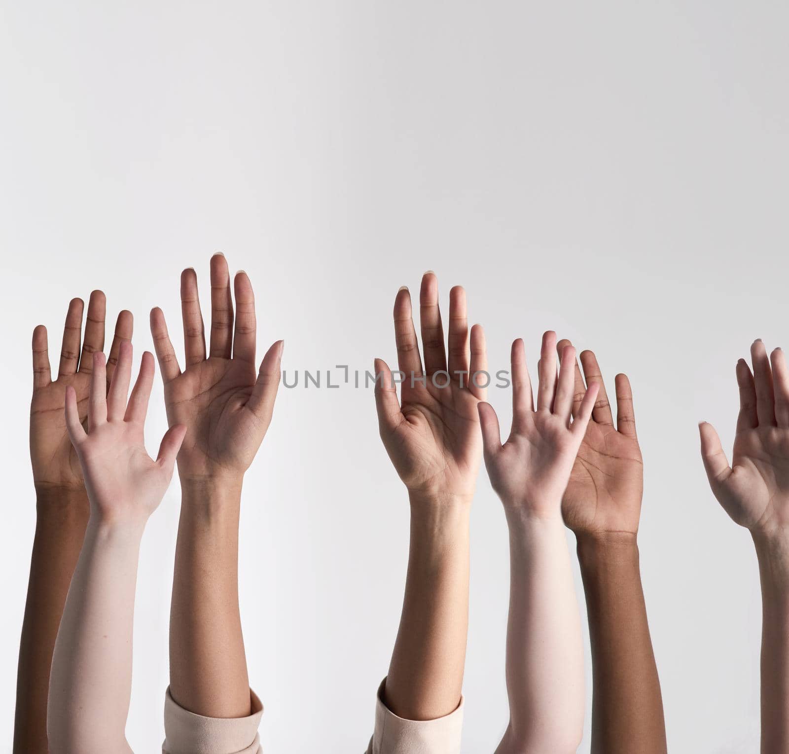 Making their voices heard. Shot of a diverse group of unidentifiable people holding their hands up against a white background. by YuriArcurs