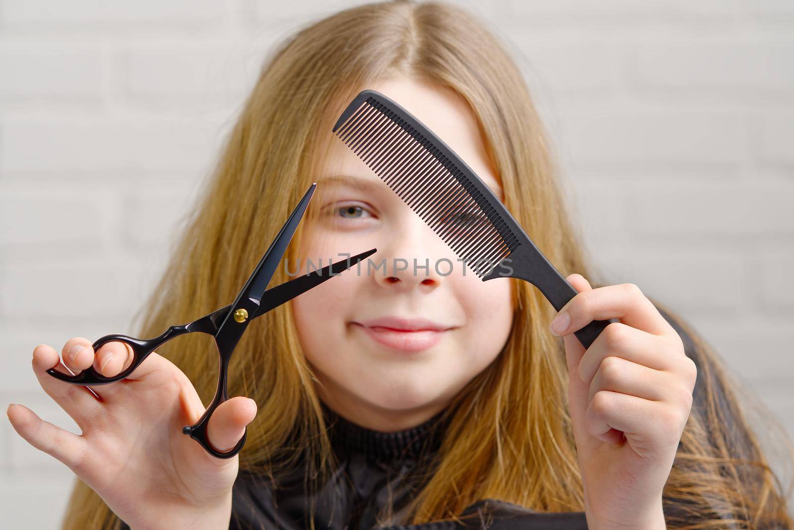 Portrait of pretty girl plays hairdresser and imagines in front of a mirror. little girl combs her hair