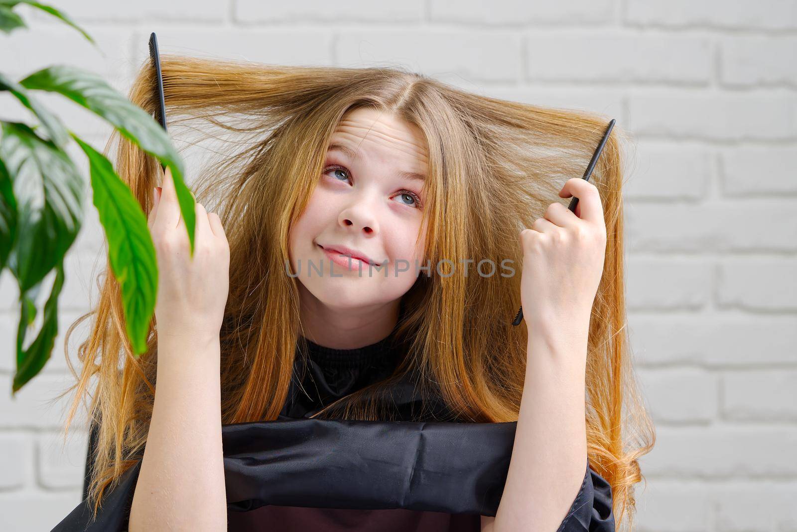 Portrait of pretty girl plays hairdresser and imagines in front of a mirror. by PhotoTime