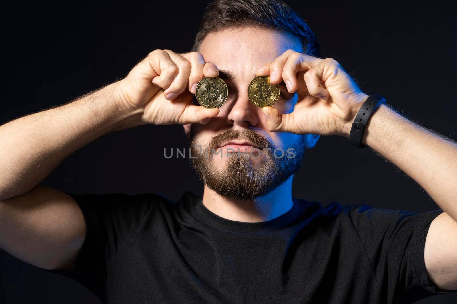 Bitcoin lover enthusiast with golden coin by eyes on black background. Digital symbol of a new virtual currency. Cryptocurrency