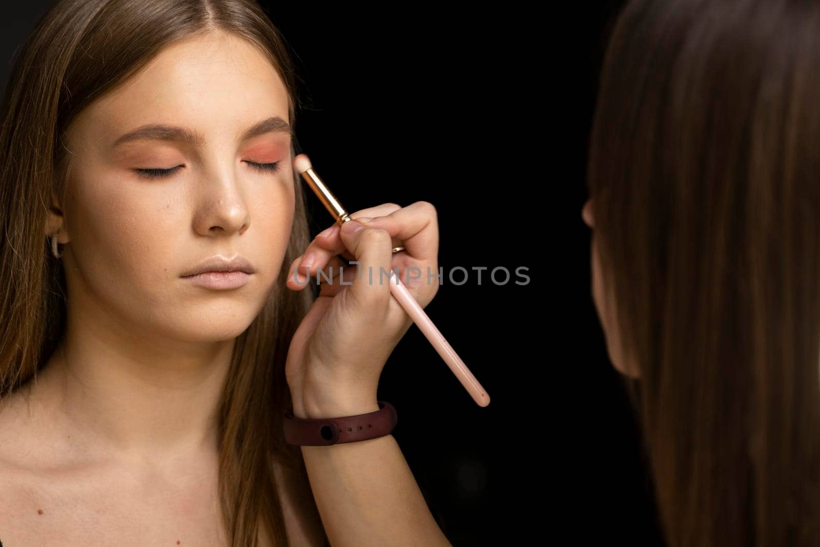 Young beautiful woman applying make-up by make-up artist. Make up in process