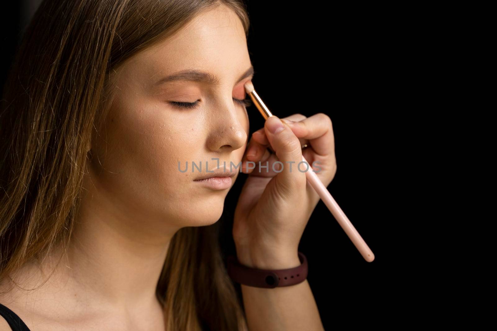 Proffesional make-up artist applying eyeshadow powder on a models eyes in beauty studio