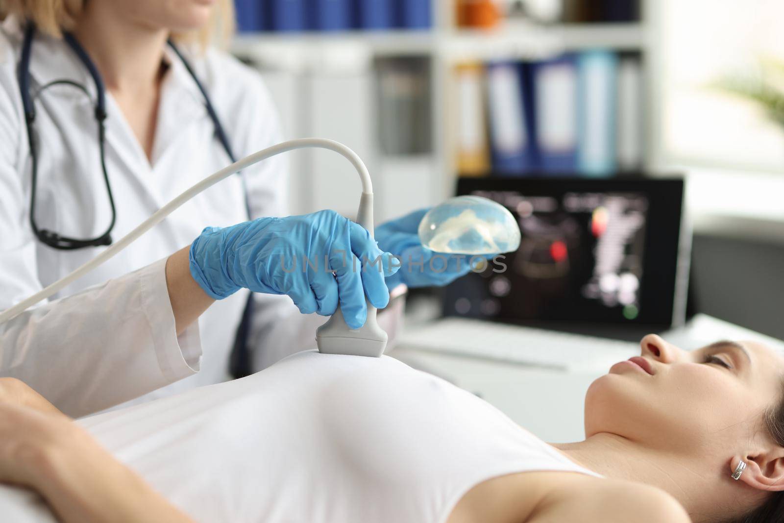 The doctor makes a woman breast ultrasound, close-up. Preparing for mammoplasty, breast cancer treatment