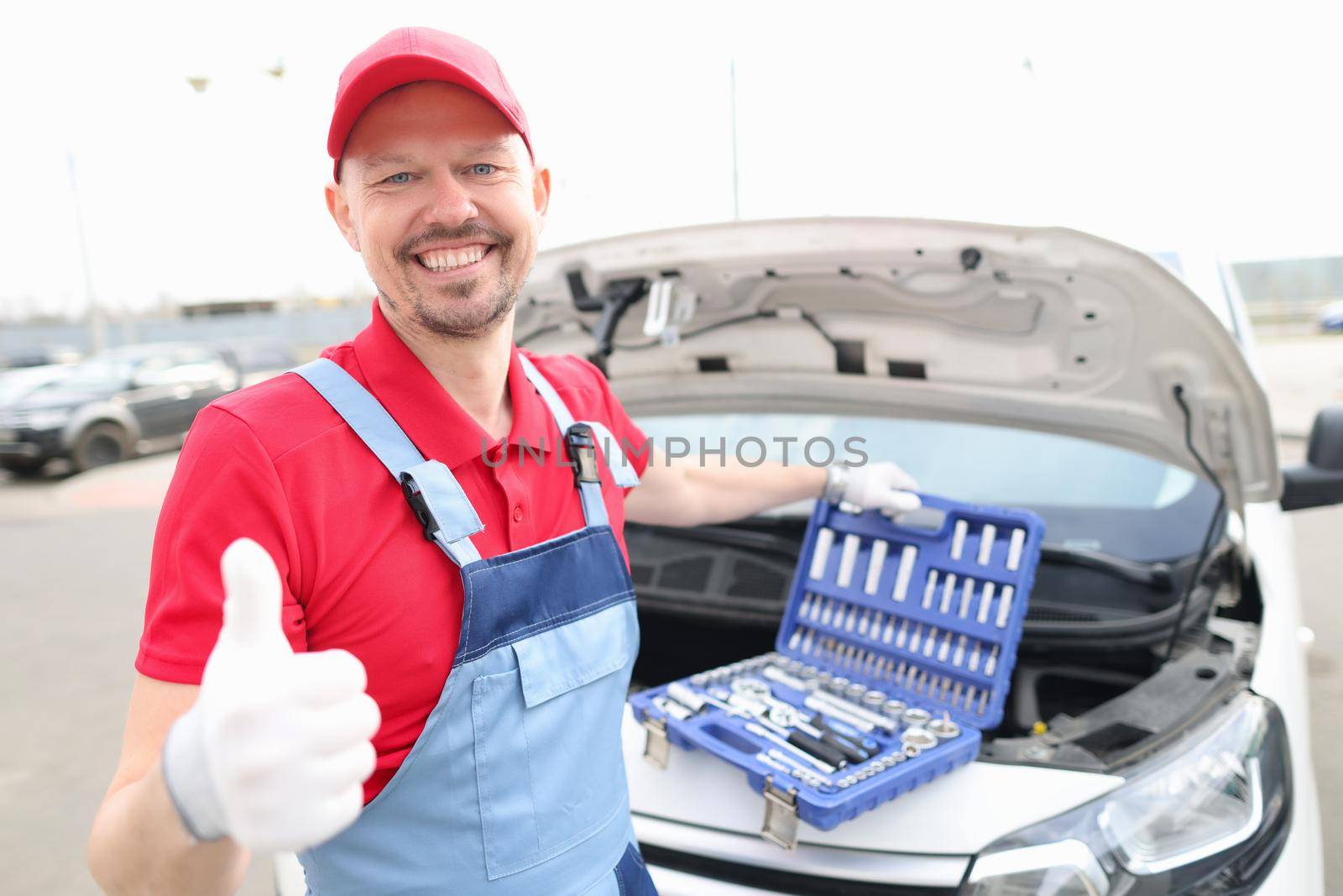 A repairman in a red uniform opened the hood car on street by kuprevich