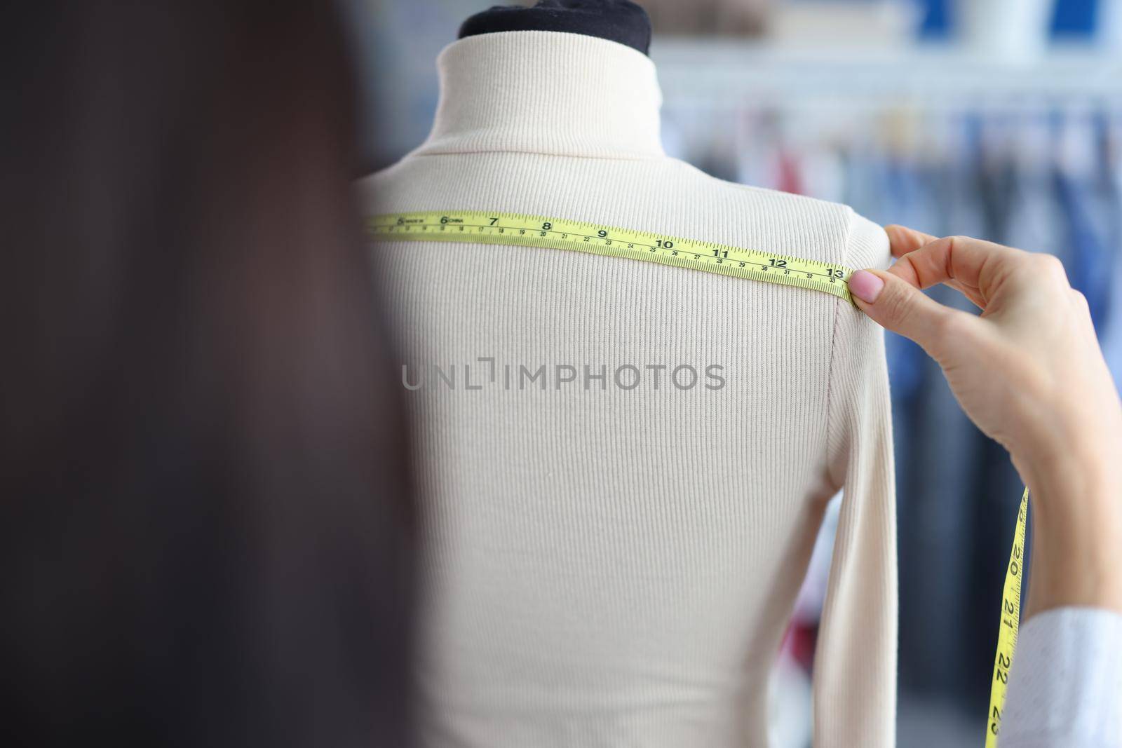 A woman measures the width with a tape on a mannequin by kuprevich