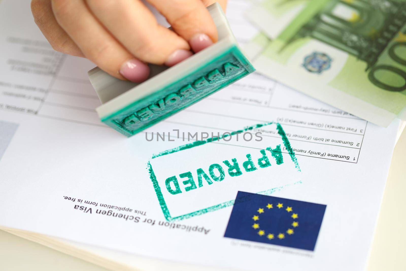 A hand puts a stamp approved on a document for a visa to Europe, close-up. Preparation of documents for a trip abroad