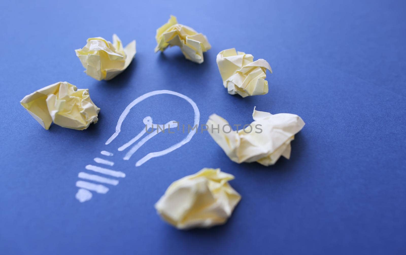 Lot of crumpled papers lying on drawn light bulb closeup. Ideas in business concept