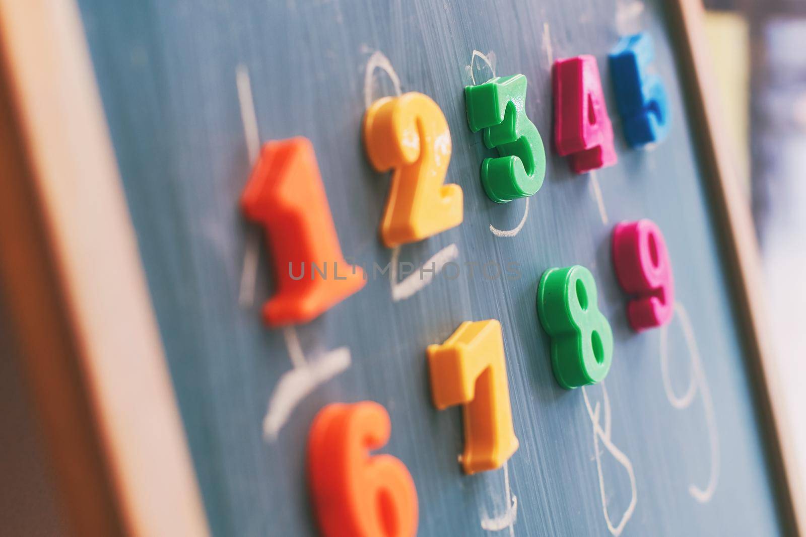 Learning numbers on a blackboard with colorful magnets and handwriting on blackboard during homeschooling. Quarantine lifestyle concept.