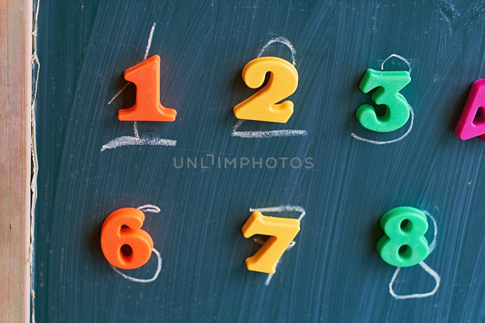 Learning numbers on a blackboard with colorful magnets and handwriting on blackboard during homeschooling. Quarantine lifestyle concept.