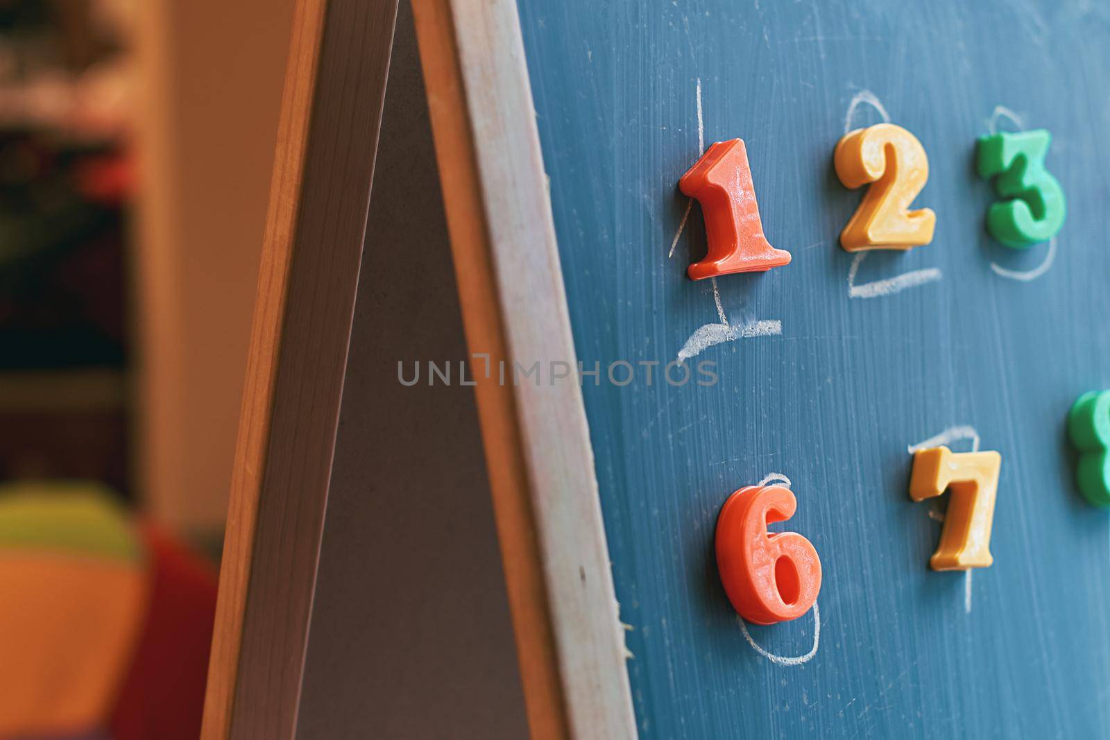 Learning numbers on a blackboard with colorful magnets and handwriting on blackboard during homeschooling. Quarantine lifestyle concept.