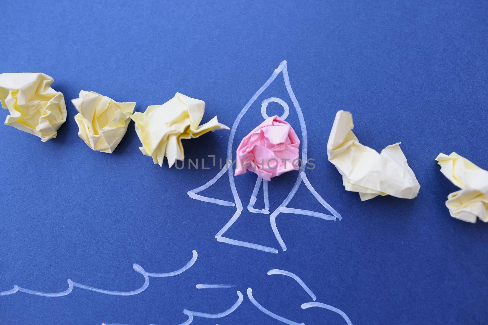 Crumpled papers lying on rocket drawn on blue background. Startup in business concept