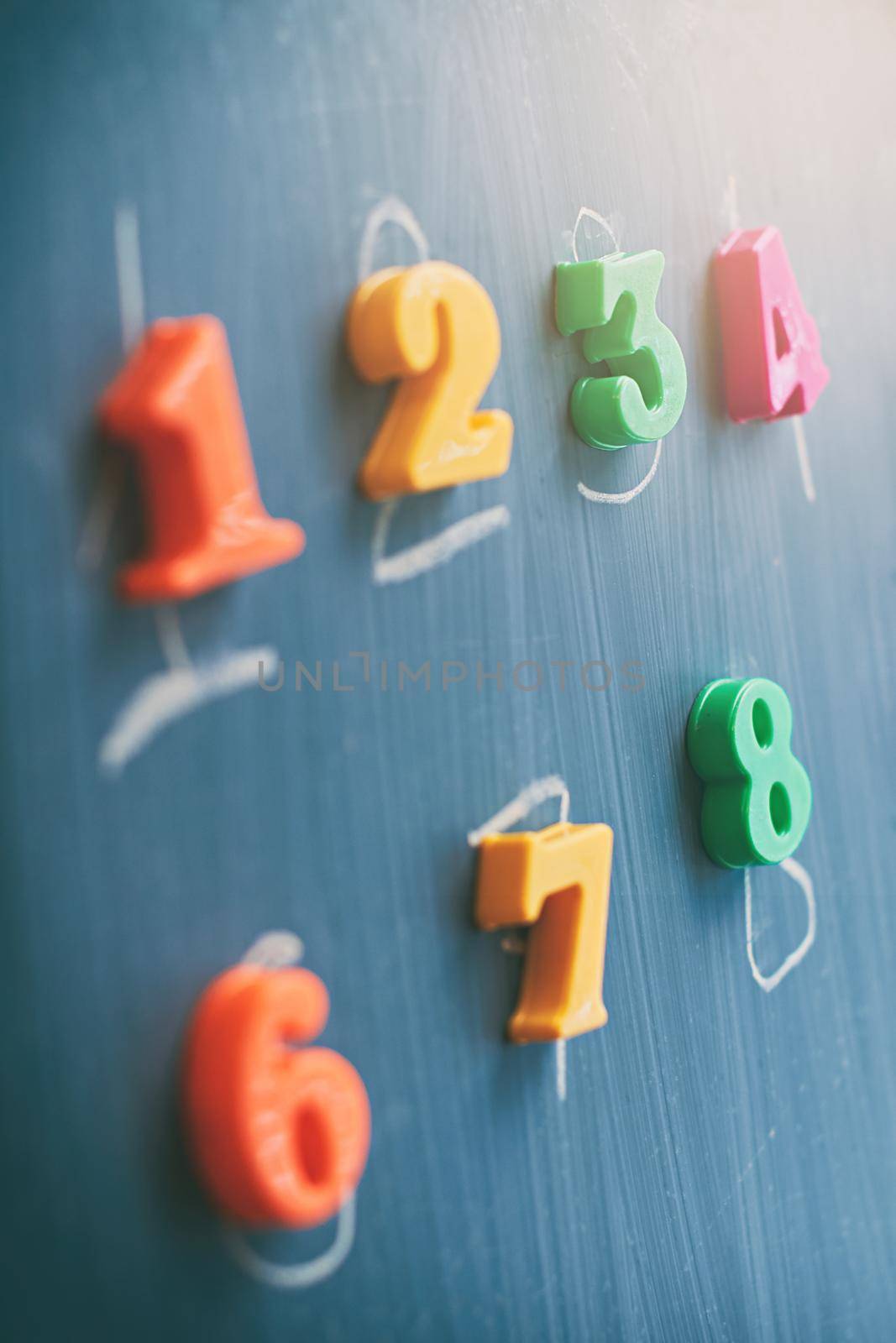 Learning numbers on a blackboard with colorful magnets and handwriting on blackboard during homeschooling. Quarantine lifestyle concept.