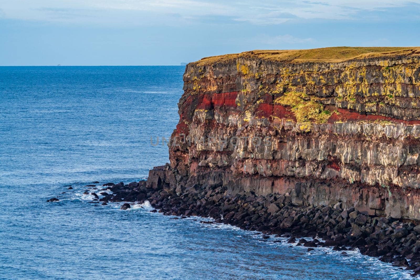 Spectacular volcanic steep cliffs with red seams in Iceland