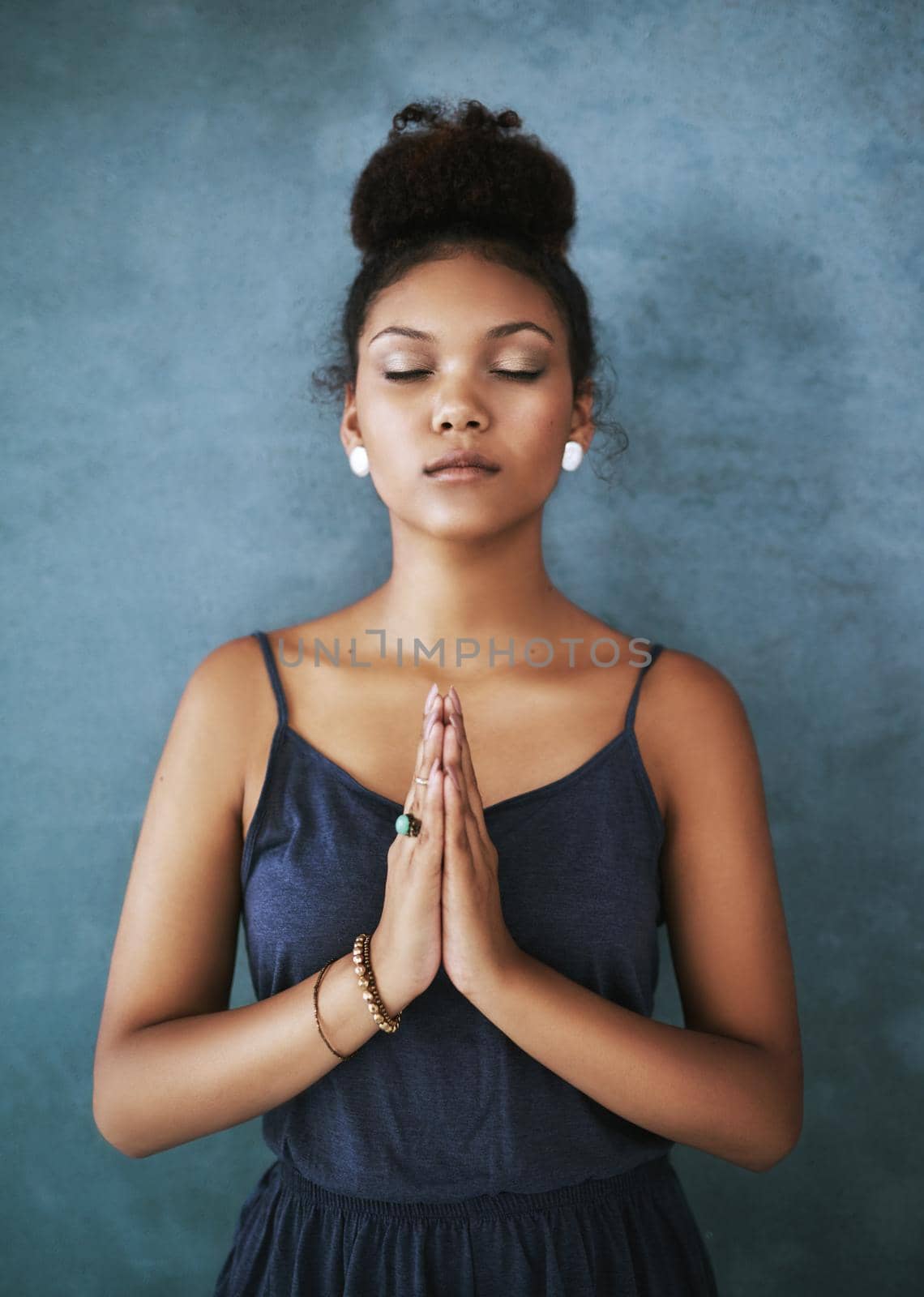 Finding inner peace. Cropped shot of a young woman meditating against a grey background. by YuriArcurs