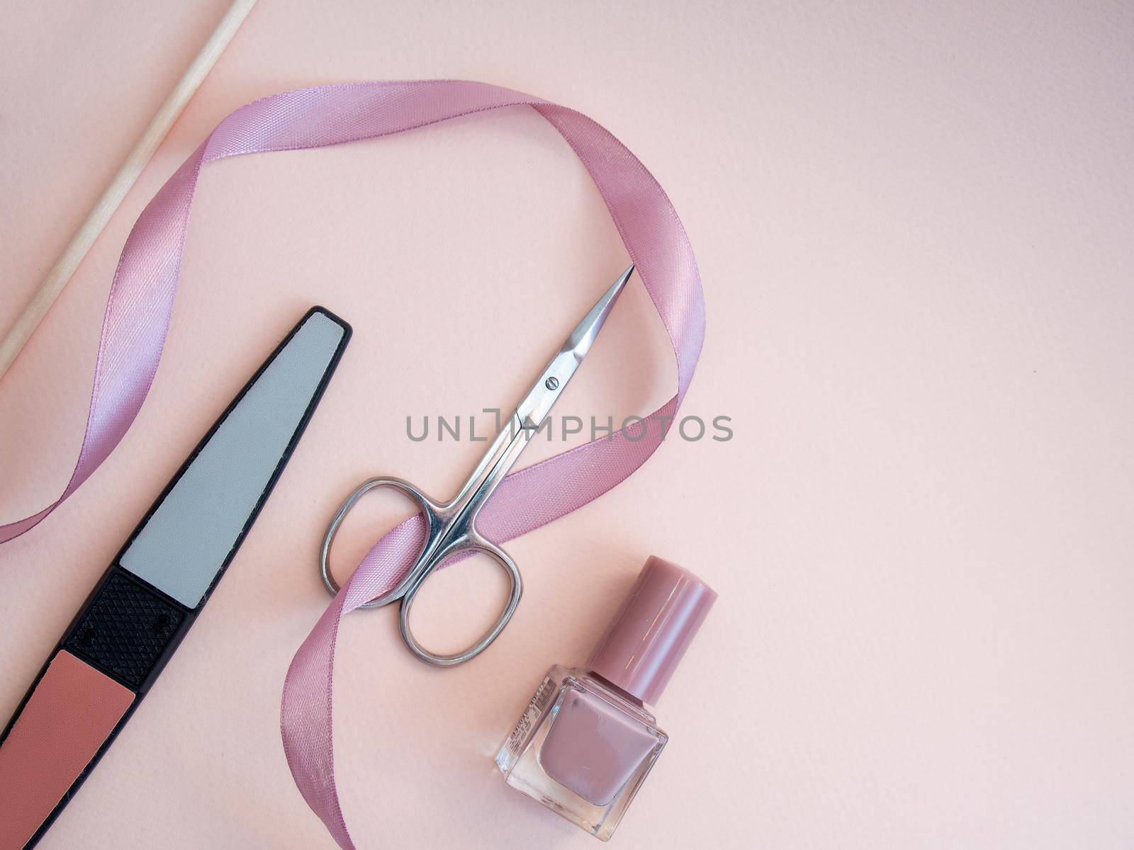 A set of cosmetic tools for manicure and pedicure on a pink background. Gel polishes, nail files, manicure scissors. photo