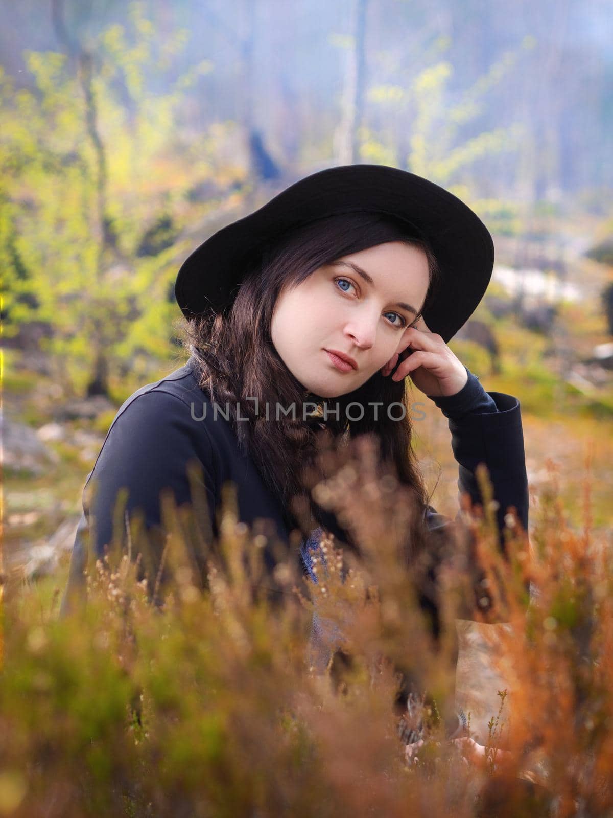 Portrait of a young girl in the autumn forest. Girl in a hat on a background of heather.
