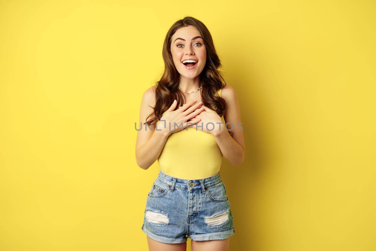 Portrait of enthusiastic, hopeful woman looking with yearning, smiling happy face, expecting smth, desire, standing over yellow background.