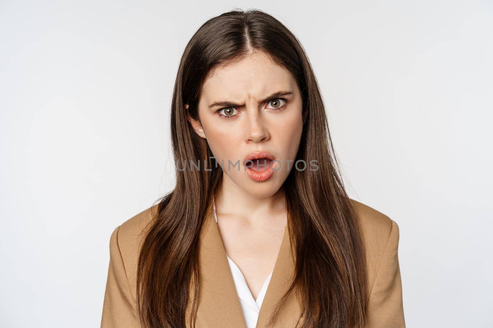 Confused office worker, businesswoman staring shocked and insulted at camera, standing over white background. Copy space