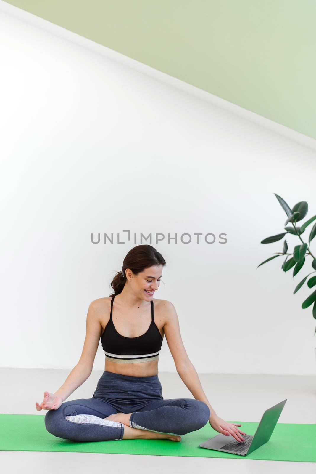 Young woman doing sports and yoga at home using a laptop. Advertisement for yoga courses