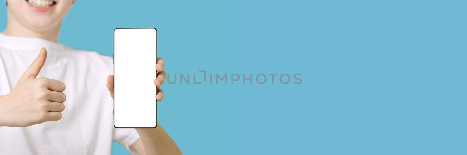 Happy smiling boy showing smartphone mockup in a blue backdrop. mobile phone , cellphone screen mockup, banner