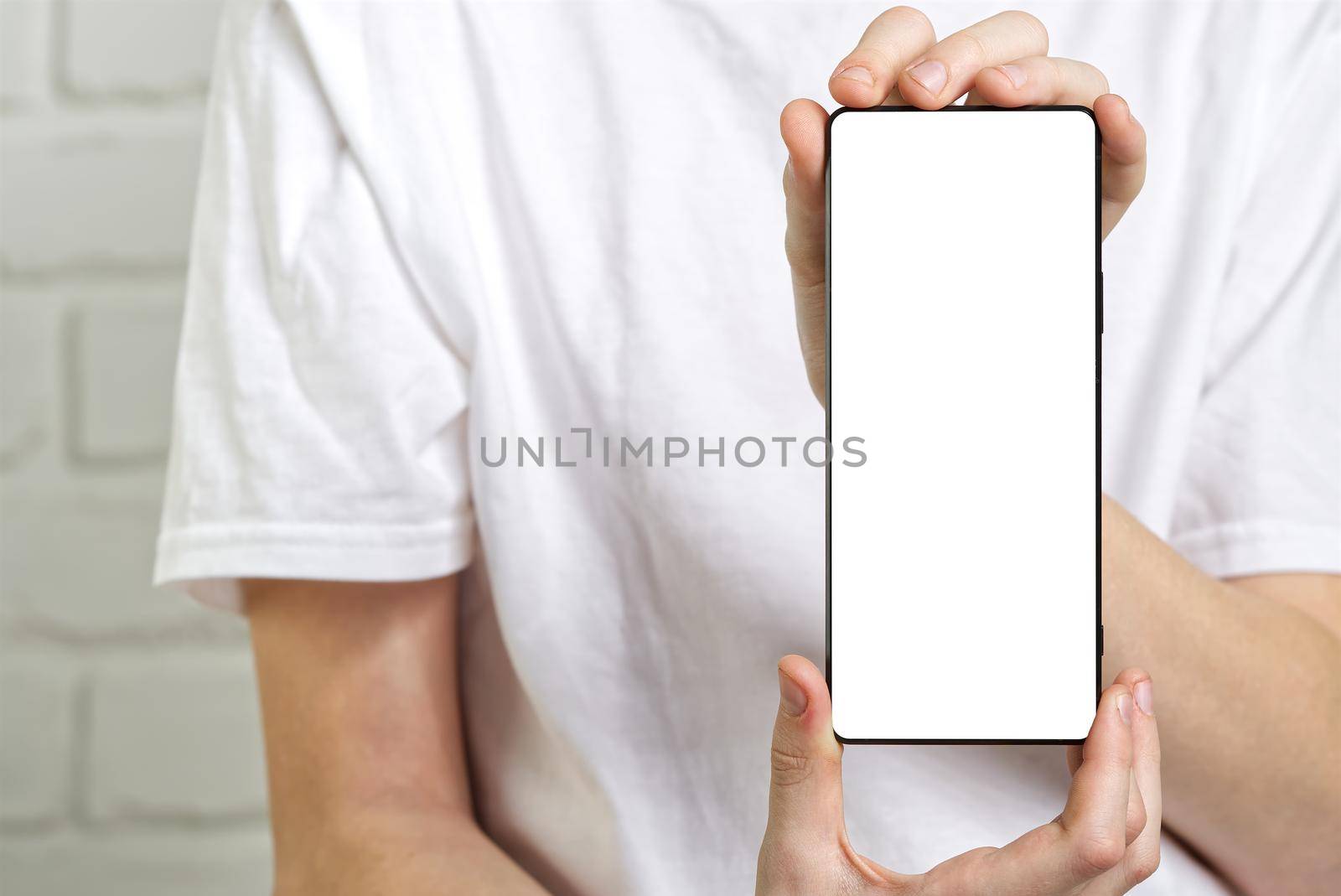 Happy smiling boy showing smartphone mockup in a white backdrop. mobile phone , cellphone screen mockup