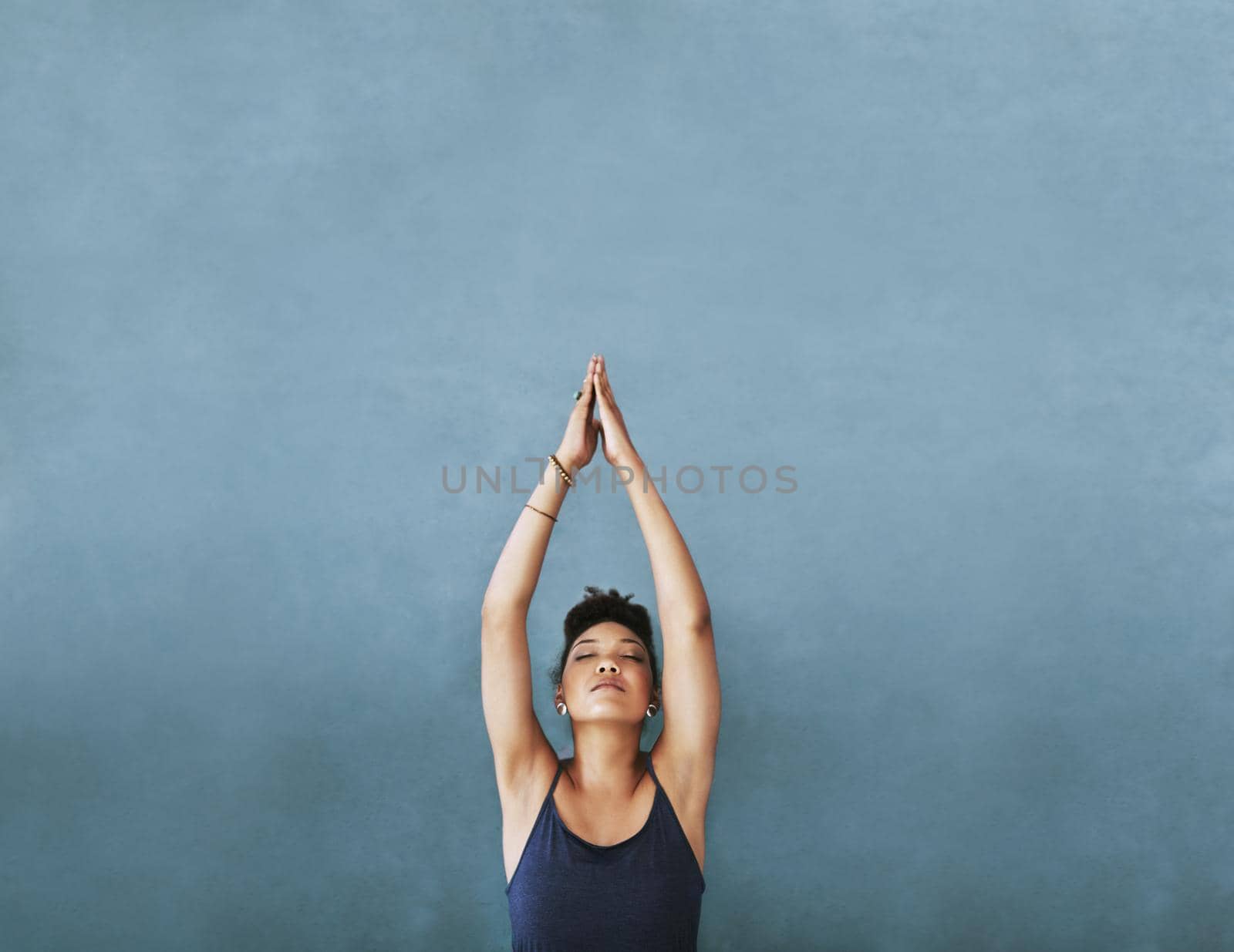 Cropped shot of a young woman meditating against a grey background