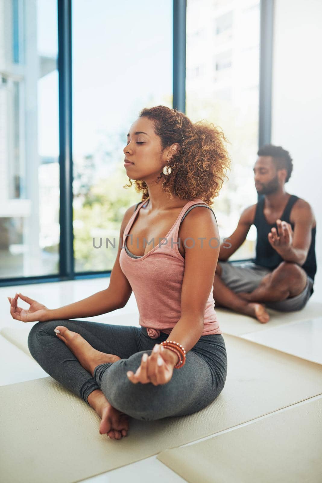 Shot of two people doing yoga together in a studio