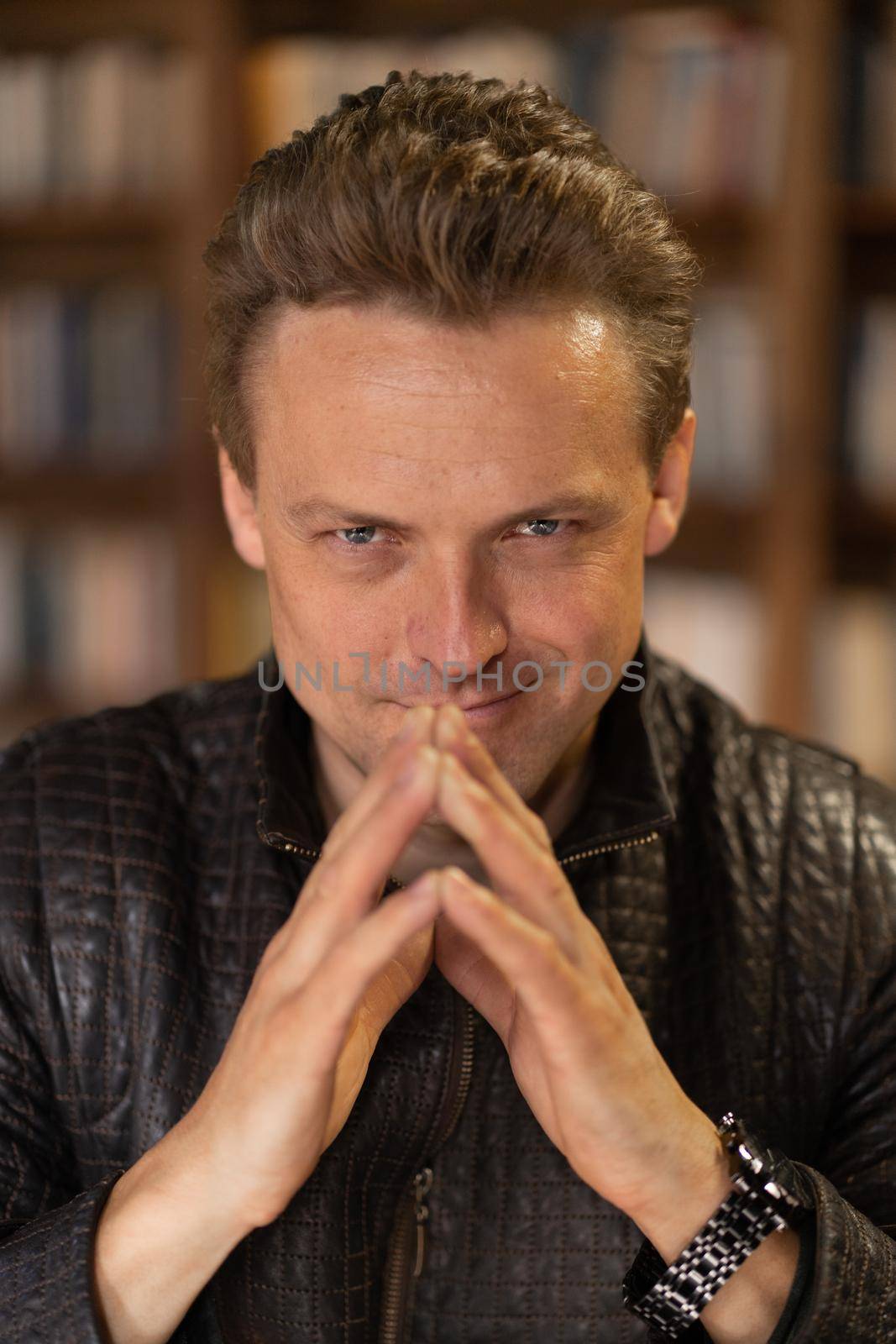 Caucasian Mature Man Slyly and Piercingly Looks into the Camera. Attractive Blonde Guy of 35s with the Eyes of an Experienced Lawyer. Close-up Face Portrait. Blurred background by LipikStockMedia