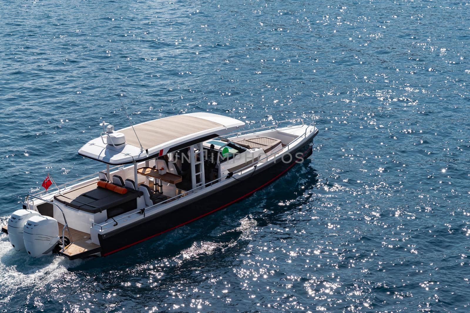 The large luxury boat on the background of blue water, port of Hercules in Monaco, sunny glare of the sun on the water, powerful boat, glossy surfaces shine in sunny weather. High quality photo