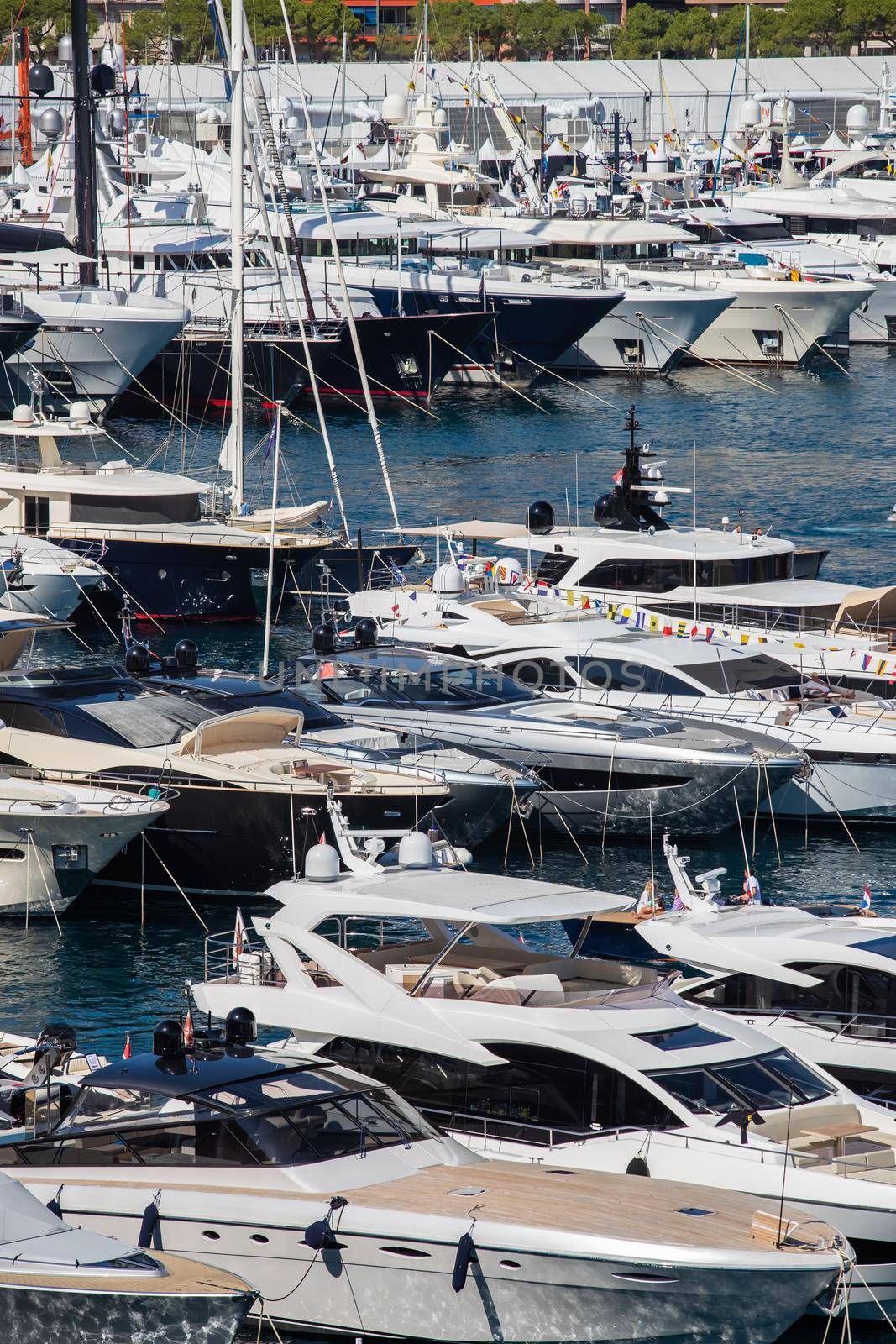 A lot of huge yachts are in port Hercule of Monaco at sunny day, Monte Carlo, many small boats are on background, interiors of motor boat, chilling zone of megayachts, sun reflections on glossy boards. High quality photo