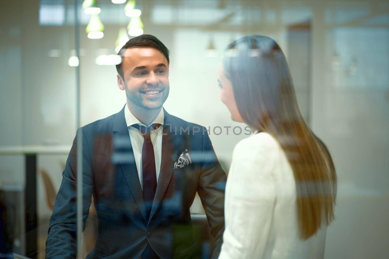 Diverse millennials in formal outfit business partners talking after meeting sitting in a modern bright working place. Handsome young businessman and a woman cooperating working in the office.