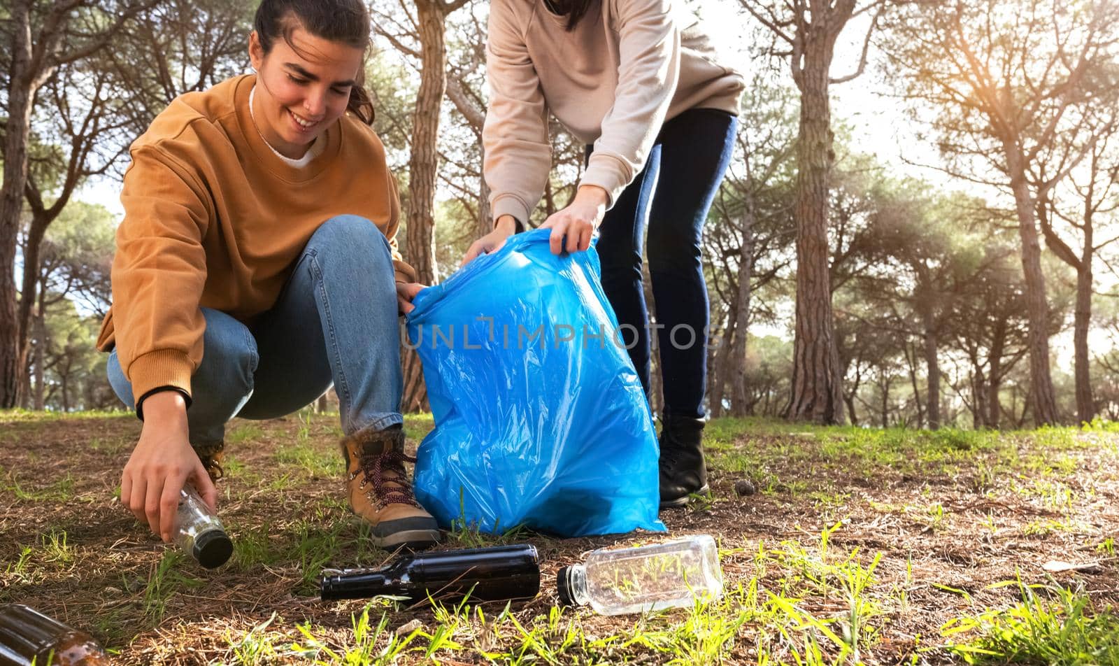 Caucasian young women clean forest together. Help environment. Copy space. by Hoverstock