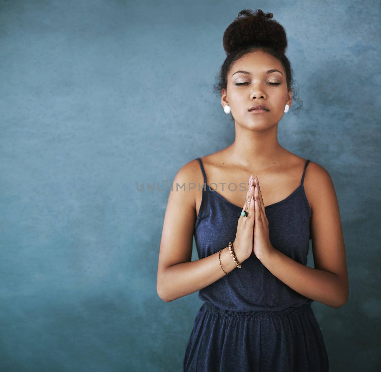 Finding her center. Cropped shot of a young woman meditating against a grey background. by YuriArcurs