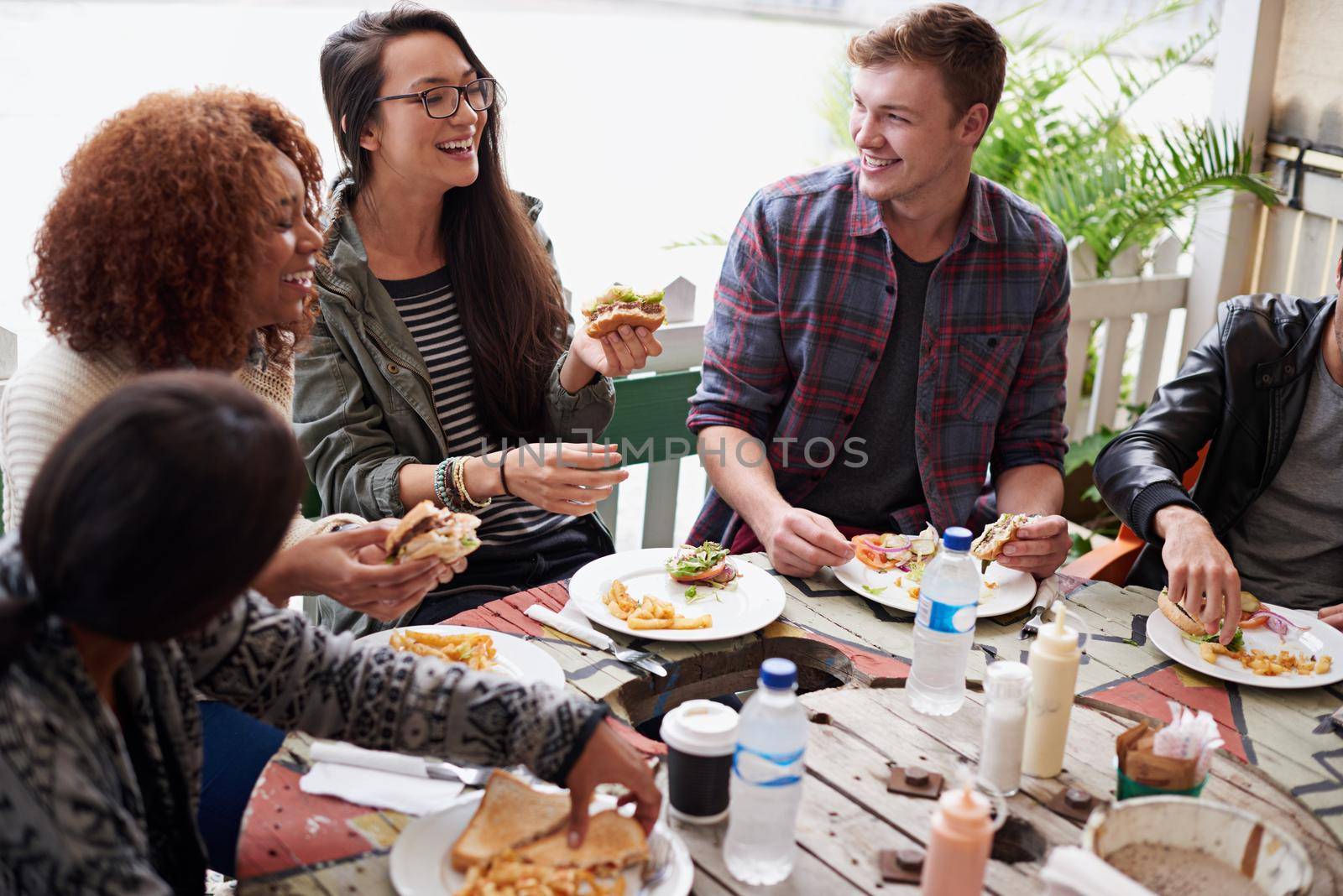 Cropped shot of a friends eating burgers outdoors