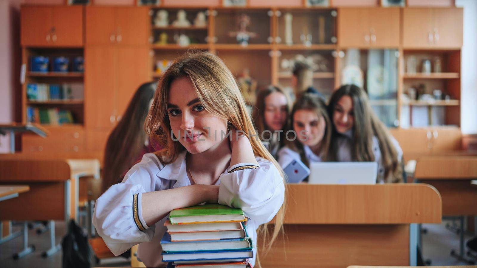 A student poses with textbooks at her desk in her class