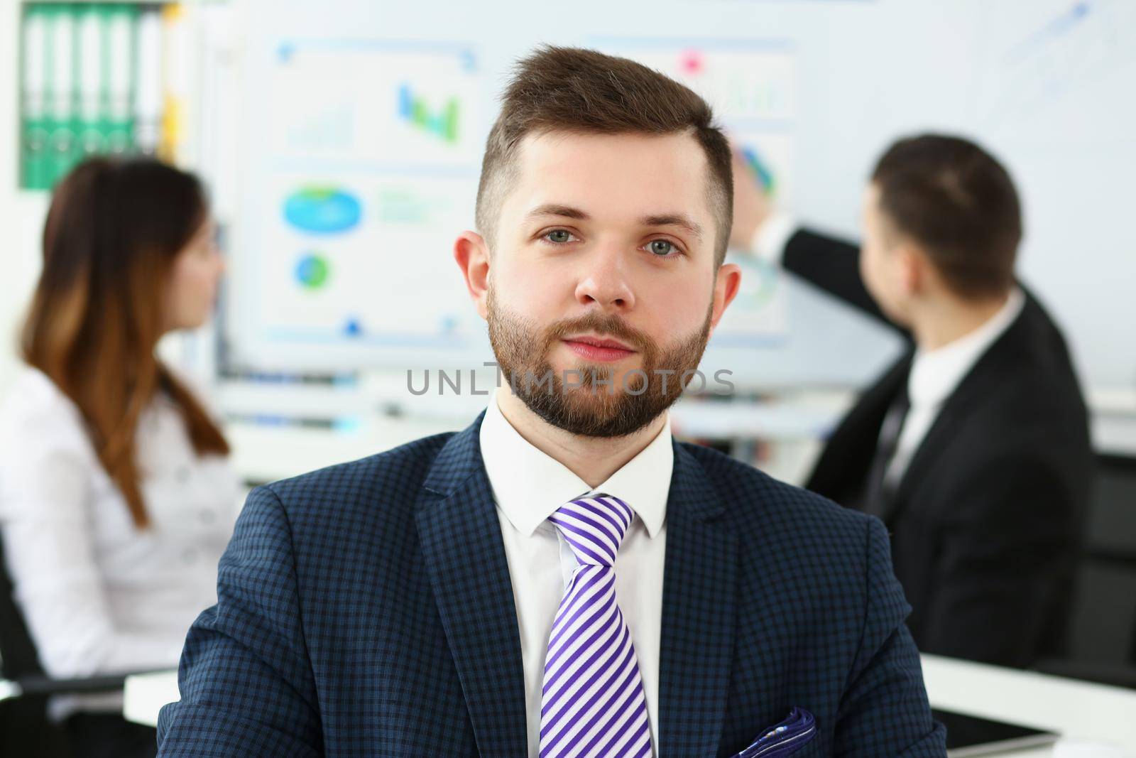 Portrait of businessman in office in presentable suit, colleagues on background near board. Success, human resources, business, corporate, career concept